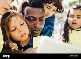 Teacher and students in kindergarten playground Stock Photo