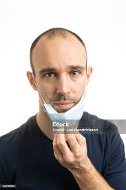 A White Male Pulling His Mask Down With A Neutral Expression Stock Photo