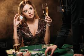 Beautiful woman holding glass of champagne and poker chip at table ...