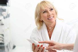 Beautician Hand Is Pointing Finger At Tube Confidently. Mature Lady Is  Smiling And Looking At Cosmetologist With Trust Stock Photo, Picture and  Royalty Free Image. Image 64895249.
