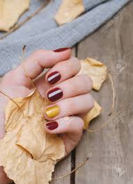 While gold is compassion and wisdom, glamour. Female Hand With Dark Red Nail Design Holding Yellow Leaves Stock Photo Picture And Royalty Free Image Image 107951400
