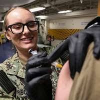 Hospital Corpsman 2nd Class Emanuel Floyd administers a flu vaccination to  Lt. j.g. Chad Peritore during a SHOTEX in the hangar bay of the aircraft  carrier USS Harry S. Truman (CVN 75). -