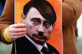Una persona sostiene un cartel que muestra a Vladimir Putin vestido como Adolf Hitler, durante una protesta contra la operación militar de Rusia en Ucrania, frente a la Embajada de Rusia en