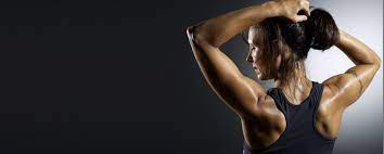 Muscular woman wearing fitness clothing posing against black background. Group Fitness Music Mixes Cardio Aerobic Workout Music Legal Music