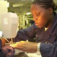 Ship's Serviceman Seaman sews patches