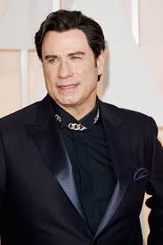 John Travolta 2024 Dunkelbraun Haar & überkämmen Haarstil.
