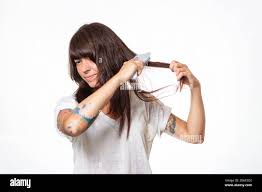 Una Mujer Con Tatuajes Peina Un Mechon De Cabello Experimentando Dolor Y Sacando Su Cabello Fondo Blanco Espacio De Copia El Concepto De La Perdida Del Cabello Y El Cuidado Fotografia De