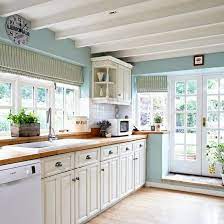 A candle chandelier that doubles as a pot rack hanging over the taupe kitchen island that's paired with black bar stools. Cream Country Kitchen Ideas Kitchen Ideas