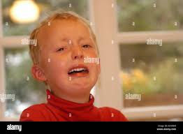 Blonde kurzhaarige traurig Kind weint mit Tränen in seinen blauen Augen  Stockfotografie