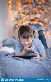 «cinco lobitos tiene la loba cinco lobitos detrás de la escoba. Feliz Nino Guapo Con Una Tablet En Las Manos Los Ninos Juegan A Los Juegos De Ordenador En Tableta Nino Se Acuesta En La Cama De Imagen De Archivo Imagen De