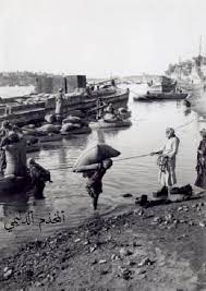 صورة تراثية توثق لعملية تفريغ الحبوب من لزوارق والكلك والقفف في بغداد في بداية القرن الماضي photo iraq lovely