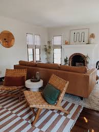 An airy beach living room with woven roman shades, a wooden table, touches of blue and turquoise, white upholstered furniture. Customize Roman Shades Belgian Linen Cotton Barn Willow Tan Living Room Living Room Shades Roman Shades Living Room