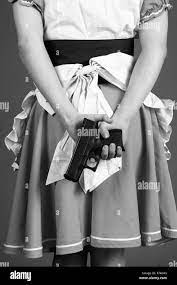 Young woman in an anomie dress with a gun behind her Stock Photo - Alamy