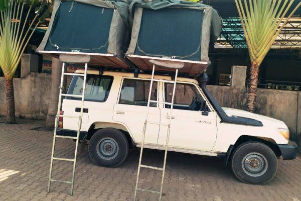 Toyota Land Cruiser Prado with a deployed rooftop tent for a Rwanda car rental with rooftop tent camping safari