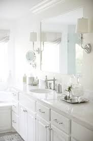 A White Framed Vanity Mirror Is Lit By Two Polished Nickel Sconces Mounted To The Mirror S Fram Custom Bathroom Vanity Bathroom Countertops Bathroom Sink Decor