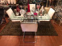 Characterized by the bold use of color and contrast often with metallic and glass accents, hollywood regency is dramatic, opulent and usually looks forward to making a statement. Hollywood Regency Lucite And Glass Dining Table With Four Chrome Chairs Fleur De Lis