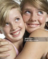 Two Girls Embracing Looking Up Smiling Closeup High-Res Stock Photo