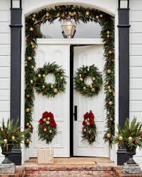 Rustic christmas front door styling with large bells, evergreens, snowy pinecones and magnolia leaves plus plaid ribbons. Outdoor Christmas Decorating In 4 Steps Balsam Hill Blog