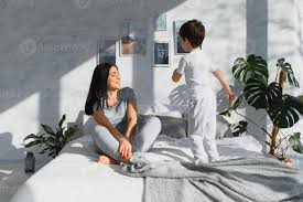 mamá jugando con su niño en el dormitorio. madre con hijo compartiendo  bueno emociones mientras relajante a hogar. hijo saltando en el cama.  46389120 Foto de stock en Vecteezy