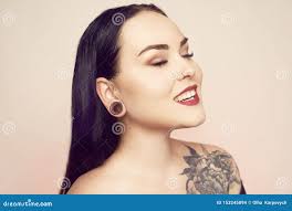 Portrait of a Brunette with a Tunnel in Her Ears, and a Pierced Nose.  Beautiful Duvushka with a Professional Make-up Stock Photo - Image of  closet, pastel: 153245894