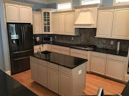 A bold orange cabinet color provides a brilliant contrast to this room's crisp black countertops and shiny white backsplash. Bone White With Glaze 2 Cabinet Girls