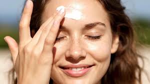 woman applying sunscreen to forehead outdoors