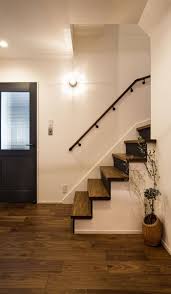 玄関ホール 重厚な色 艶が特徴のウォールナットを使用した床材 木肌の温かみを感じる無垢の建具はディープグレー色にすることで 玄関ホールの印象を引き締めます タンブラ スイッチやマリンテイストのブラケットライトを採用し ヴィンテージ感のあるお洒落な空間を