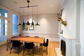 Black dining room table topped with light brown wood, surrounded by matching black chairs with seat cushions upholstered in light gray fabric. How To Use Black To Create A Stunning Refined Dining Room