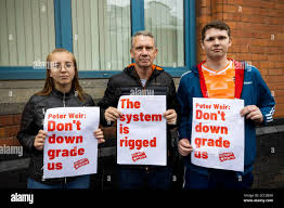 left to right) Klaudia Kita, Colin Patterson and his son, Ethan Patterson,  during a protest outside the Northern Ireland Education Authority main  building in Belfast, over Northern Ireland Minister of Education Peter
