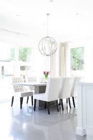 Light And Bright Dining Room Features A Gray Pedestal Dining Table Lined With White Wingback Dining Cha Transitional Dining Room Chic Dining Room Dining Chairs