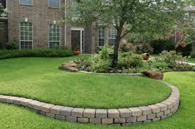 A Curving Retaining Wall Of Tumbled Concrete Blocks Snakes Across A Terraced S Front Yard Landscaping Design Landscaping Retaining Walls Front Yard Landscaping