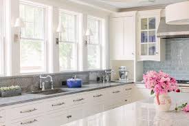 Shiny white cabinets sit above the countertops and complement the textured tile backsplash. White Kitchen Cabinets With Gray Granite Countertops And Backsplash Transitional Kitchen