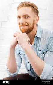Charming bearded men looking at camera with Easter egg decoration in his  beard
