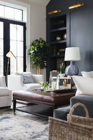 A Brown Leather Tufted Ottoman Sits On A Silver And Blue Rug Between A Gray Velvet Sofa And Side By Side Living Room Grey Brown Living Room Living Room Leather