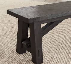 A large round dining table in a walnut finish with a rustic finish. Toscana Dining Bench Pottery Barn