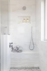 Gorgeous bathroom features a tub nook with barrel ceiling lined with honed calacata herringbone tiles, walker zanger tangent chevron, filled with a modern freestanding tub and floor mount tub filler placed in front of windows dressed in peacock blue curtains layered over taupe roman shades alongside an ash gray and honed calacata tiled floor, walker zanger astral night. Bathroom Chevron Tiles Design Ideas