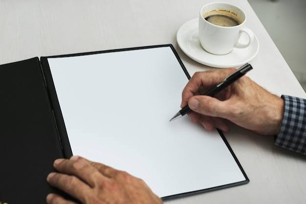 Hand writing documents next to coffee cup