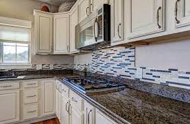 White shaker cabinets are installed on the right wall of the space, aimed to contrast the black countertops and brown subway tile backsplash. White Kitchen Cabinets With Dark Countertops Designing Idea