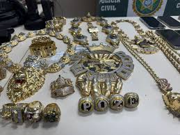 Joias de ouro e prata, incluindo colares, anéis e pingentes com leões e coroas, apreendidas pela Polícia Civil.