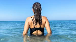 Beachgoer wading in warm coastal water amid Vibrio vulnificus health warning