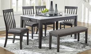 Black oak dining table with beige rattan chairs in a transitional dining room boasting a staggered bulb chandelier from a charcoal gray plank ceiling. Benchcraft Luvoni 6 Piece Dark Charcoal Gray Dining Set D464 25 4x01 00 Big Sandy Superstore Oh Ky Wv