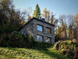 The stone walls that extend through the house into the landscape is organizing the house in axis along with specimen trees. Modern Stone Cabin In Northern Italy Is A Romantic Gem