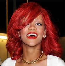 One side of her hair has been swept back and tucked in behind her ears; Rihanna Long Red Wavy Hair