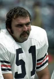 The legendary Chicago Bears Hall of Fame linebacker Dick Butkus tackles  several Packers in the hopes that he has tackled the one with the football. 