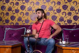 Joven De Fumar Shisha Al Restaurante Árabe - Hombre Exhalando La Inhalación De Humo A Partir De Una Pipa De Agua Fotos, retratos, imágenes y fotografía de archivo libres de derecho. Image
