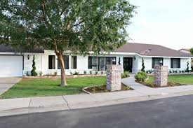 With black shutters and bright green, manicured lawn / garden with black iron flower urns. Ranch White Brick House With Black Windows Novocom Top