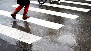 Peatones usando un cruce de cebra bien señalizado cerca del centro histórico de Lima, con una señal preventiva visible