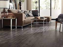 Grey is a perfect color: Comfortable Living Area With Dark Laminate Floors Brown Couch Living Room Brown Laminate Flooring Grey Flooring