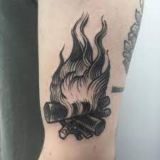 A Traditional Black Tattoo Of A Campfire Inked On The Left Arm Traditional Black Tattoo Traditional Tattoo Trendy Tattoos
