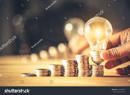 Hand Holding A Light Bulb With Coins Stack Creative Ideas For Saving Money Concept Money Management For The Future Money Concepts Light Bulb Money Management